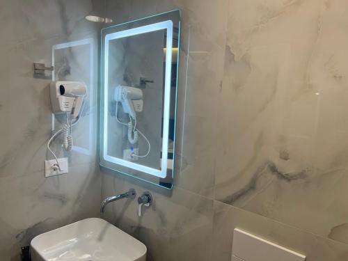 卡萨米尔Agimi Hotel的一间带镜子、水槽和电话的浴室