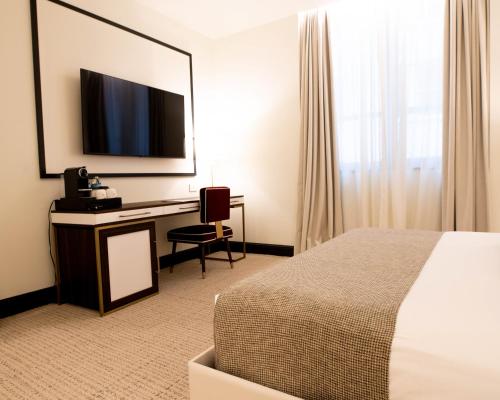 纽约纽约狄伦酒店的酒店客房配有一张床和一张书桌及一台电视