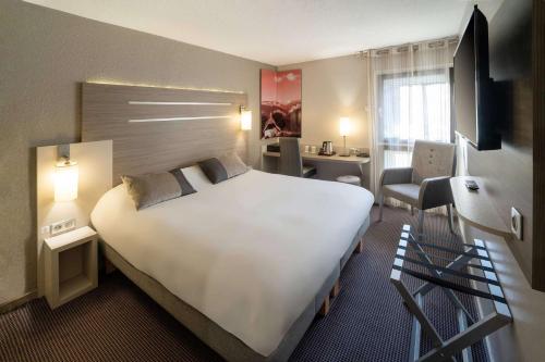瓦龙Best Western Voiron Centre的酒店客房设有一张白色大床和一张书桌