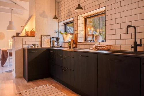 英斯约Swedish Costal Forest Hideaway的厨房配有黑色橱柜、水槽和窗户。