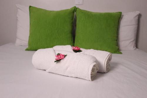 马塞约Pousada Casa Mar Pajuçara的床上的两条毛巾,带绿色枕头和鲜花