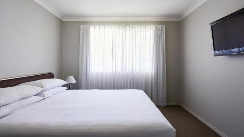 堪培拉品尼克公寓式酒店的卧室配有白色的床和窗户。