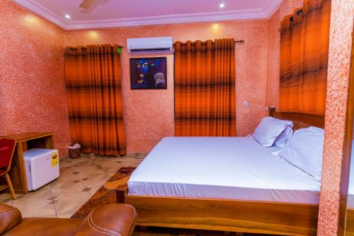 库马西Kobby Keach K Hotel的一间卧室配有带橙色窗帘的大床