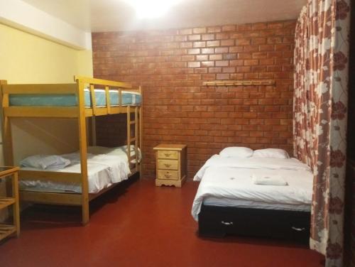 瓦拉斯ALOJAMIENTO PICSHA EXPEDITIONS的一间卧室设有两张双层床和砖墙