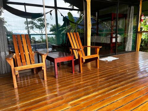 德雷克Nativos Corcovado cabins的木甲板上配有两把椅子和一张桌子