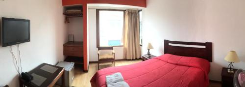 皮斯科Hostal El Candelabro的一间卧室配有红色的床和电视