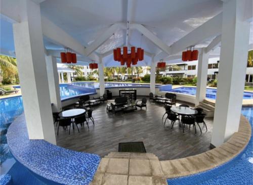 蒙特里科Agradable estancia en Monterrico的一个带游泳池和桌椅的度假酒店