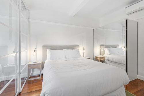 墨尔本Elegant 1-Bed CBD Apartment with Sunroom Study的白色卧室设有一张大床和镜子