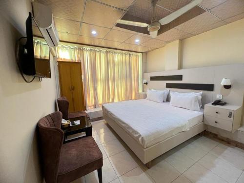 伊斯兰堡Islamabad Premium Hotel的一间卧室配有一张床、一台电视和一把椅子