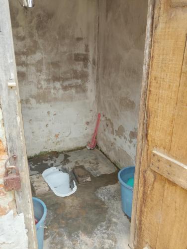 KohīmaAqhe Homestay的一间脏的房间,有水桶和厕所