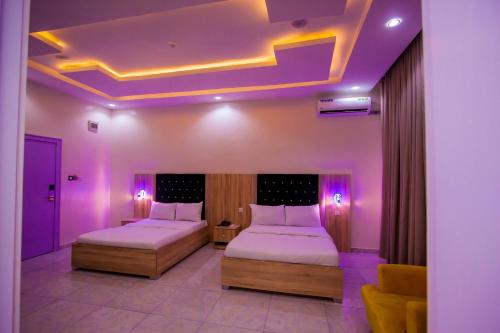 拉各斯Soulmate Hotels & Suites的紫色照明客房的两张床