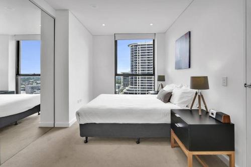 悉尼Amazing two bedroom St Leonards ATC62010的一间卧室设有两张床、一张桌子和窗户。