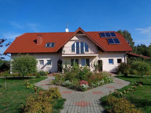 盖奇瓦乌德Gospodarstwo Agroturystyczne Leśna Polanka的一座红色屋顶的房子和一个花园