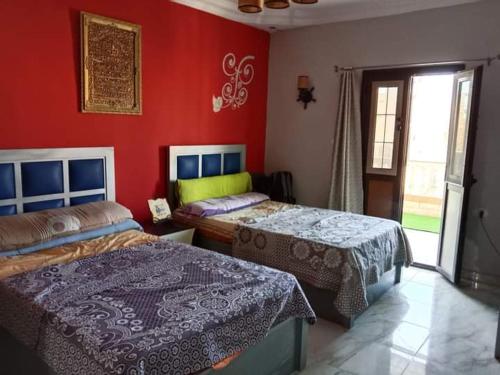 马特鲁港Marsa Matrouh的一间卧室设有两张床和红色的墙壁