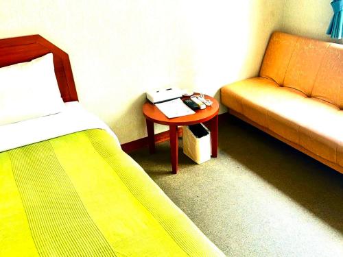 石垣岛石垣幸福假日酒店的一间卧室配有一张床、一张沙发和一张桌子