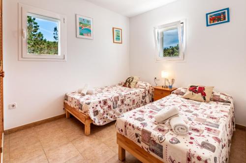 卡拉索纳Casa Es Vedrà的一间卧室设有两张床和两个窗户。