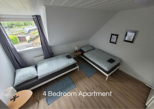 HauCozy Apartment in Bedburg-Hau的小房间设有两张床和窗户