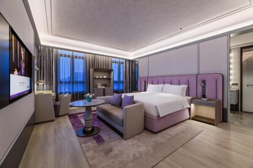 杭州杭州浙大紫金港美爵酒店的一间卧室配有一张床、一张沙发和一台电视。