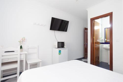 罗塔Hostal Restaurante La Giralda的一间卧室配有一张床、一张书桌和一台电视