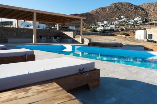 图罗斯Megusta Mykonos的一个带白色沙发椅的大型游泳池