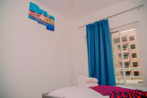 FumbaOcean Homes Zanzibar的一间设有蓝色窗帘和窗户的床的客房