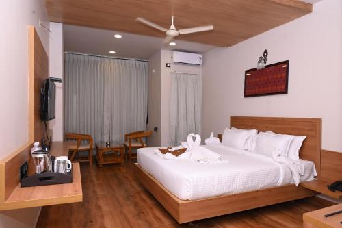 胡布利Varaha Residency Lodging and Banquet的卧室配有一张白色大床和电视。