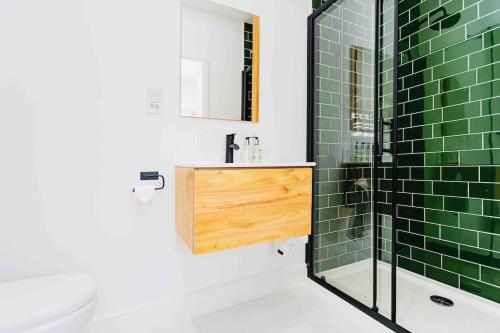 滨海巴顿Luxury Ocean Playroom SEA SALT CHALET的浴室铺有绿色瓷砖,配有水槽和淋浴。