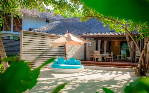 汉纳梅杜岛康斯丹马尔代夫哈拉薇莉度假酒店的庭院配有蓝色的椅子和遮阳伞。