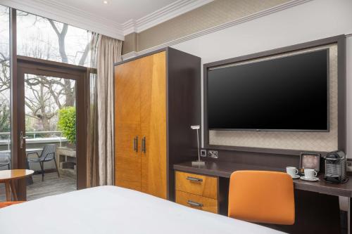 伦敦伦敦海德公园希尔顿逸林酒店的一间卧室配有一张床和一台平面电视