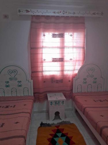 米多恩Appartement yakine的客房设有两张床和一个带粉红色窗帘的窗户。