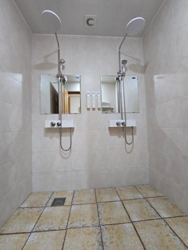 丽水市丽水南沙酒店的浴室设有两个淋浴,墙上设有镜子