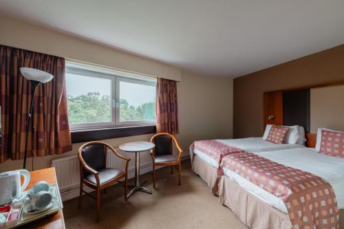 佩斯利Normandy Hotel (Near Glasgow Airport)的酒店客房带两张床和一张桌子以及椅子。