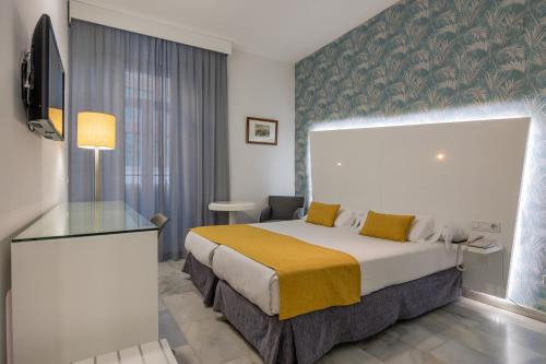 马拉加阿塔拉扎纳斯马拉加精品酒店的酒店客房设有一张床铺和一张玻璃桌