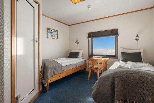 MaursetHalne Fjellstugu的客房设有两张床、一张桌子和一扇窗户。