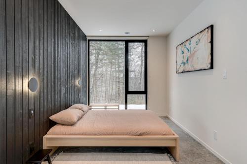 St-Etienne de BoltonAu Haut De La Colline Spa Et Sauna的一间卧室设有一张床和一个大窗户