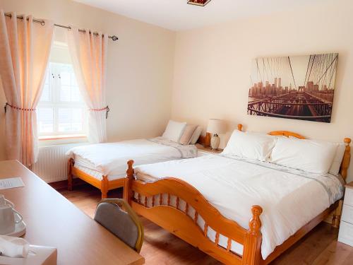 KilcarKilcar Lodge的一间卧室配有两张单人床、一张桌子和一张书桌。