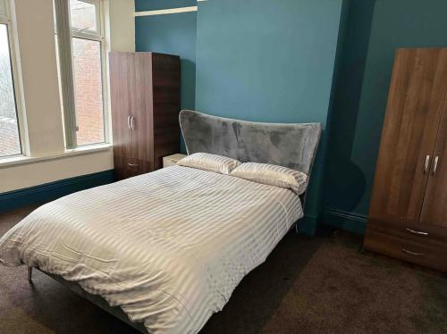 NeepsendComfortable Room in Shared Sheffield Detached House - Room 3的卧室内的一张床铺,卧室内有蓝色的墙壁