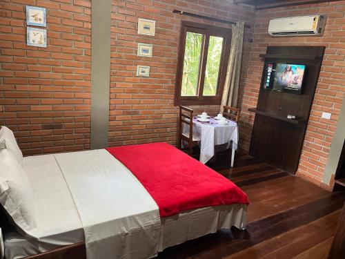 贝卢港Pousada Nosso Bosque的一间卧室配有一张带红色毯子和桌子的床。