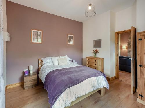 Llanvair DiscoedThornycroft Cottage的一间卧室设有一张大床,铺有木地板