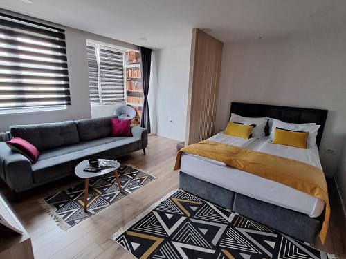 萨拉热窝Apartman Orhideja with Free Parking的一间卧室配有一张大床和一张沙发