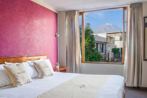 阿雷基帕Hotel Maison Du Solei的一间卧室设有粉红色的墙壁和一张带窗户的床