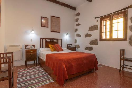 Valleseco厄尔祖玛卡尔旅馆的一间卧室配有一张带橙色毯子和窗户的床。