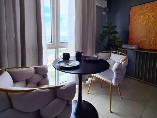 马尼拉ELUDE Designer Suite Pasig - Prime Location的一间带桌子和两把椅子的用餐室