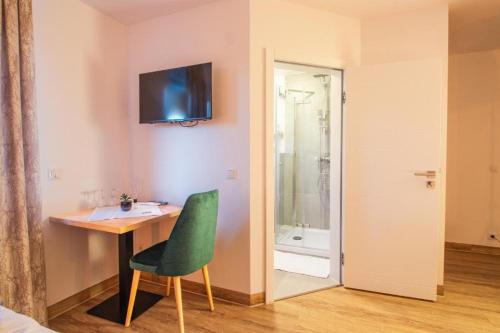 贝尔吉施格拉德巴赫Hotel Dona的客房设有带绿色椅子的书桌和淋浴