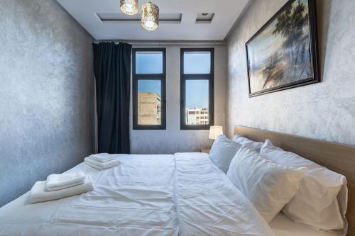 卡萨布兰卡Stylish Studio à Ain Sebaa的卧室配有一张白色大床和两个窗户