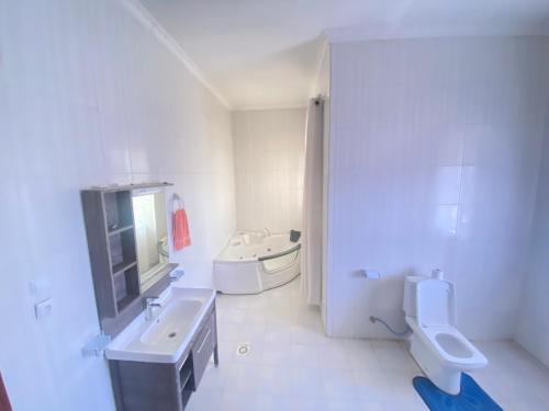 基加利Luxurious very spacious 6 bedrooms villa with pool located in Gacuriro,close to simba center and a 12mins drive to downtown kigali的白色的浴室设有水槽和卫生间。