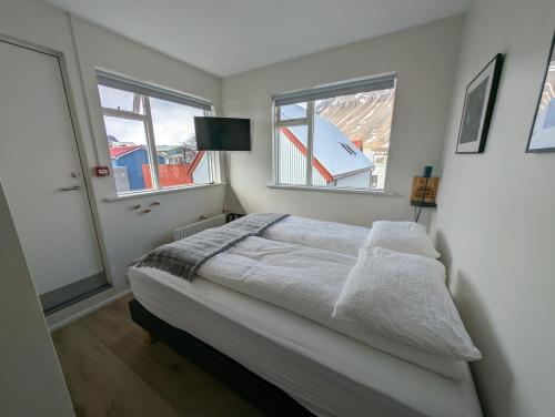 伊萨菲尔德The Ísafjörður Inn的一间白色卧室,配有床和2个窗户