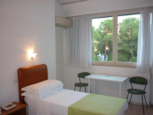 安德里亚Albergo dei Pini的一间卧室配有一张床、一张书桌和一个窗户。