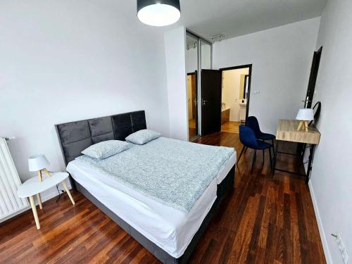 华沙FIRST -- Green Żoliborz apartment 3的卧室配有1张床、1张桌子和1把椅子