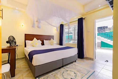 内罗毕Markson Hotel Kilimani的一间卧室配有一张床、一张书桌和一个窗户。